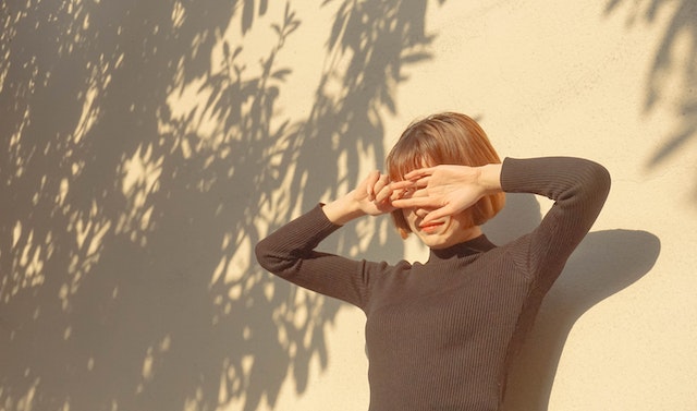 Frau deckt sich die Augen vor der Sonne mit der Hand zu.